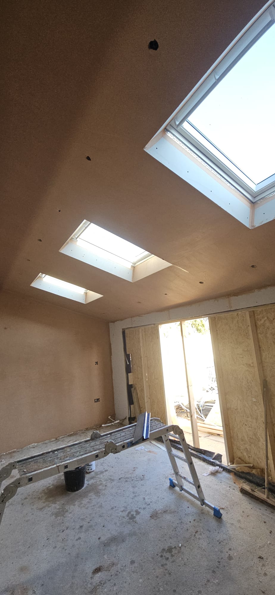 Freshly plastered vaulted ceiling and walls inside a new extension, with three roof windows letting in daylight
